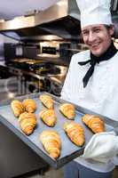 Portrait of a chef holding tray of croissants