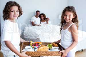 Portrait of daughter and son carrying breakfast tray for parents