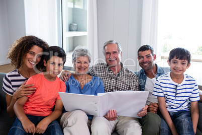 Portrait of happy family sitting on sofa and looking at photo al