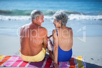 Cute mature couple sitting on a towel on the beach