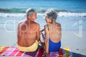 Cute mature couple sitting on a towel on the beach