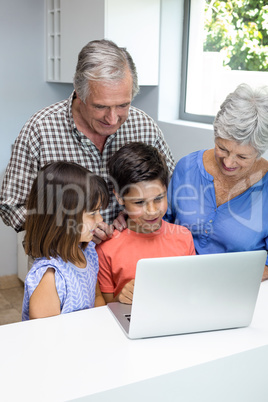 Grand parents and grandchildren interacting using laptop