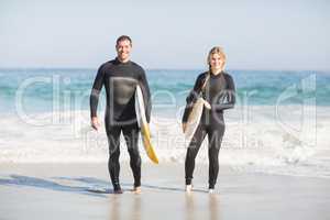 Portrait of couple with surfboard walking on the beach