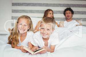 Portrait of siblings relaxing with parents on bed