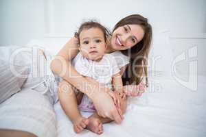 Portrait of woman with baby girl on bed