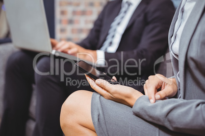 Midsection of business people using mobile phone and laptop Midsection of business people using mobile phone and laptop