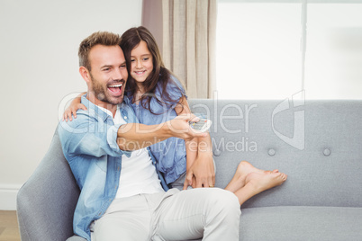 Smiling daughter and father watching television