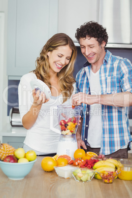 Smiling couple preparing fruit juice
