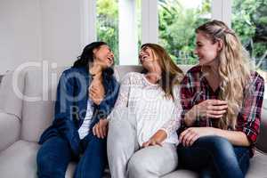 Cheerful female friends sitting on sofa