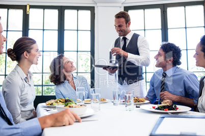 Waiter serving water to business people