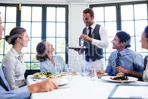 Waiter serving water to business people