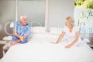 Happy senior couple talking while sitting on bed