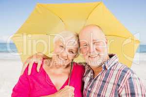 Smiling senior couple holding umbrella