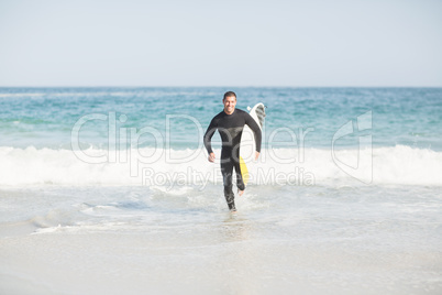 Surfer running on the beach with a surfboard