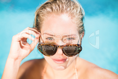 Portrait of beautiful woman wearing sunglasses leaning by poolsi