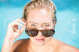 Portrait of beautiful woman wearing sunglasses leaning by poolsi