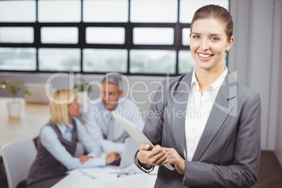 Businesswoman using digital tablet in background at office
