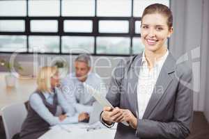 Businesswoman using digital tablet in background at office