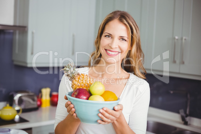 Portrait of smiling woman holding fruit bowl