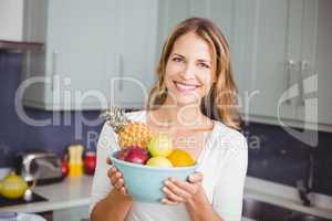 Portrait of smiling woman holding fruit bowl