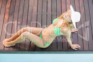 Beautiful woman in green bikini sitting by pool side