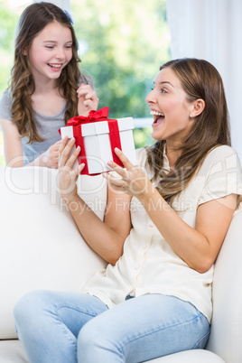 Surprised woman holding gift with daughter