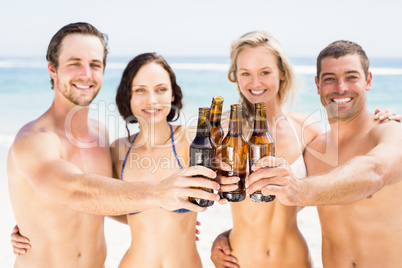 Portrait of happy friends toasting beer bottles on the beach