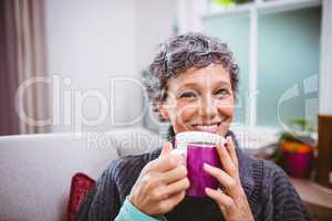 Happy mature woman drinking coffee at home
