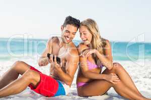 Happy couple sitting back to back on beach