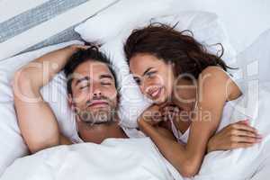 Smiling woman looking at man relaxing on bed