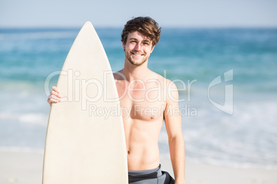 Handsome man holding surfboard on the beach