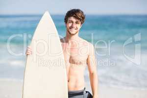 Handsome man holding surfboard on the beach