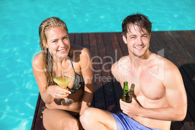 Young couple sitting at the swimming pool