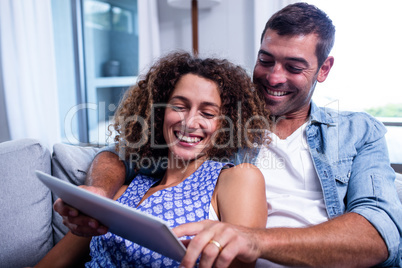 Young couple using a digital tablet on sofa