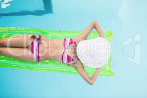 Beautiful woman in bikini lying on air bed in swimming pool