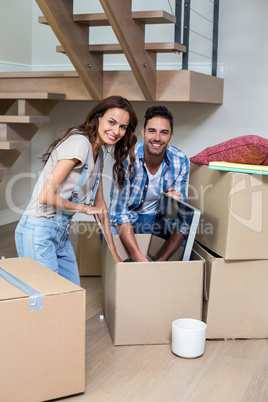 Portrait of smiling couple unpacking computer from cardboard box