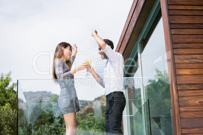 Couple dancing while drinking cocktails in balcony