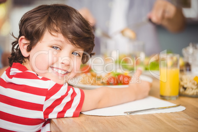Portrait of happy boy having breakfast with family