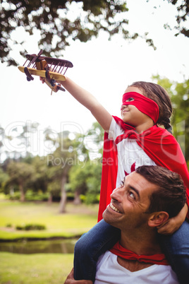 Girl in superhero costume sitting on fathers shoulders with a to