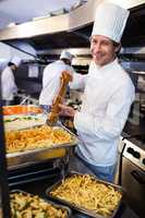 Chef grinding pepper over pasta