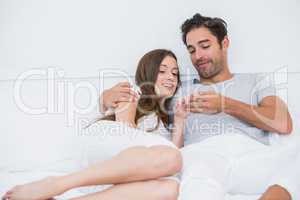 Couple looking at wedding ring while relaxing on bed
