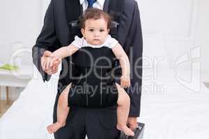 Midsection of father carrying baby and briefcase