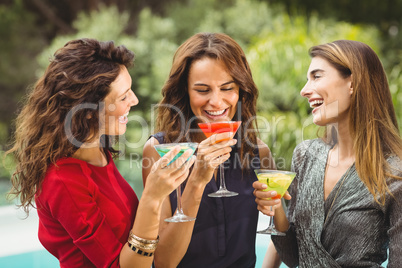 Female friends laughing while drinking cocktail