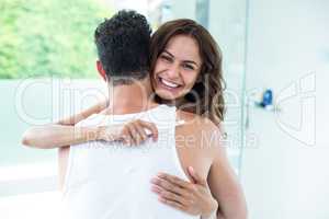 Woman hugging husband while holding pregnancy kit
