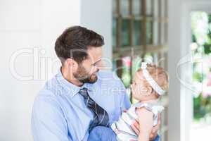 Cheerful businessman carrying daughter