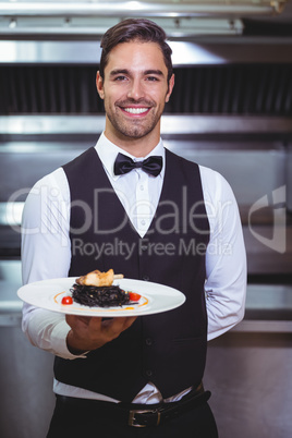 Handsome waiter holding a plate of squid ink spaghetti