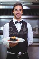 Handsome waiter holding a plate of squid ink spaghetti