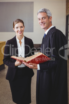 Male lawyer holding book while standing with female colleague