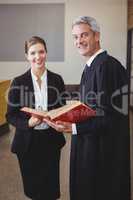 Male lawyer holding book while standing with female colleague