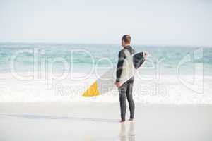 Surfer standing on the beach with a surfboard